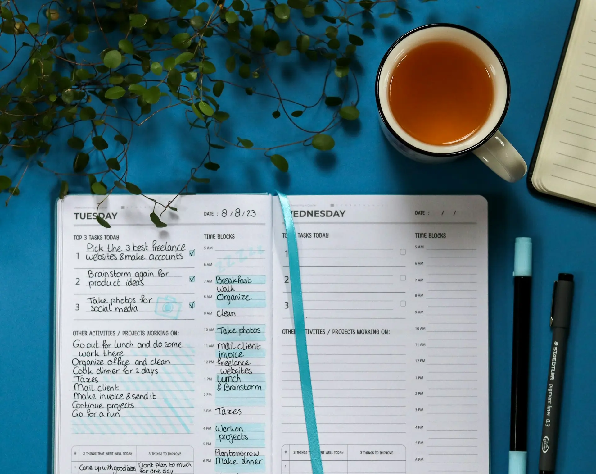a notebook with a list and a pen next to a cup of tea